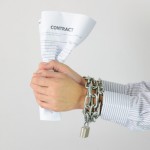 Businessman hands with chains and contract