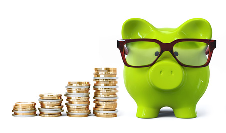Green piggy bank with glasses and coin stacks in ascending order