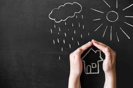 hands protects a house from the elements - rain or storm. Chalk and chalkboard.