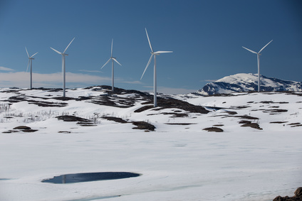 Wind turbines on a snowy hill against clear blue sky in Swedish Lapland