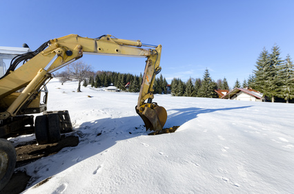 Industrial excavator loading soil material at winter snow construction site