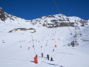 people skiing on a ski slope full of snow in a clear winter day . chair lift on the right