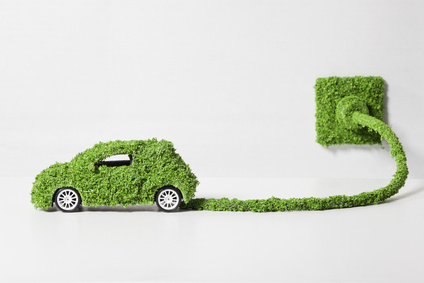 Electric car covered with grass connected to socket, close up