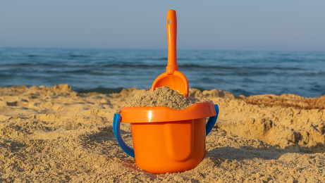 A bucket and shovel in the sand of a beach ,closeup, copy space. Beach and holiday concept.