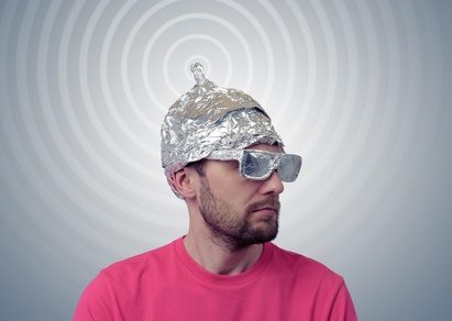 Bearded funny man in a cap of aluminum foil sends signals