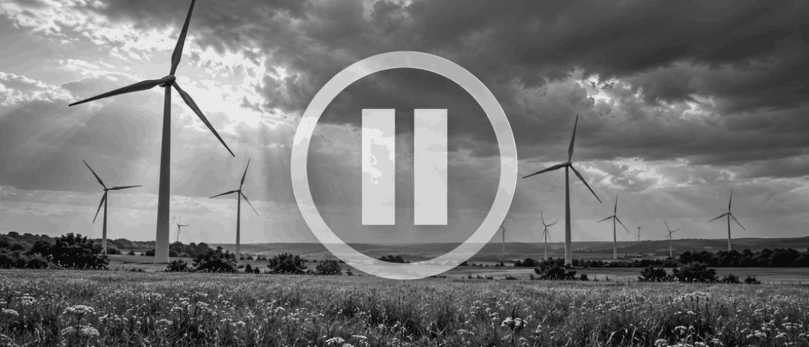 Parc éolien en noir et blanc avec un symbole de pause illustrant une suspension liée à l’absence de dérogation espèces protégées